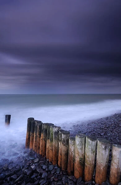 Weathered groyne, pebbles and stormy evening sky at Bossington beach, Exmoor National Park