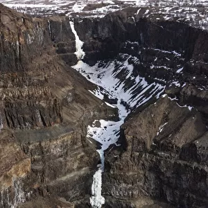 Aerial view of frozen waterfalls in deep canyon in plateau, Putoransky State Nature Reserve, Putorana Plateau, Siberia, Russia. May, 2021