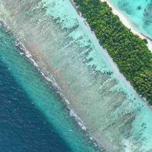 Aerial view of narrow coral atoll island with palm trees and white sand beach surrounded by reef, Dhigurah Island, South Ari Atoll, Maldives, Indian Ocean. February, 2020 Aerial view of narrow coral atoll island with palm trees and white sand beach surrounded by reef, Dhigurah Island, South Ari Atoll, Maldives, Indian Ocean. February, 2020