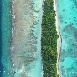 Aerial view of narrow coral atoll island with palm trees and white sand beach surrounded by reef, Dhigurah Island, South Ari Atoll, Maldives, Indian Ocean. February, 2020 Aerial view of narrow coral atoll island with palm trees and white sand beach surrounded by reef, Dhigurah Island, South Ari Atoll, Maldives, Indian Ocean. February, 2020