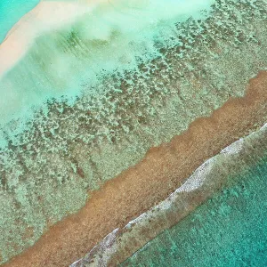 Aerial view of waves breaking on reef edge and sand bank, along South Ari Atoll, Maldives, Indian Ocean. February, 2020