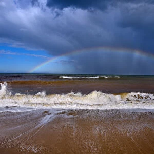 Autumn high tides with stormy skies and rainbow over the sea, Walcott, Norfolk, England