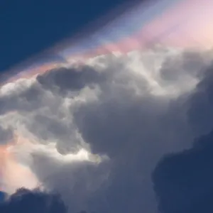 Cloud iridescence forming above a cumulonimbus cloud, caused by light refraction