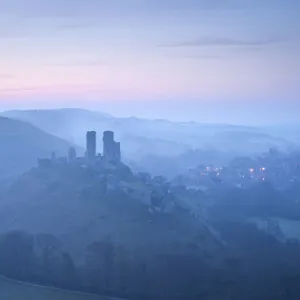 Corfe Castle, sunrise and early morning mist, view from West Hill, Corfe, Dorset, England, UK