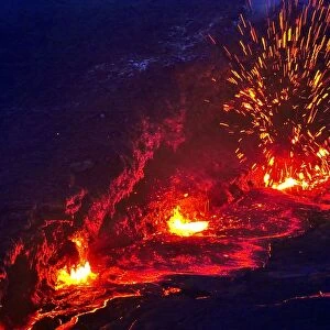 Eruption and molten lava flowing down the sides of the Erta ale volcano (the smoking