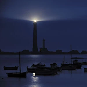 Fishing boats and lighthouse at night on the island Ile Vierge, Brittany, France