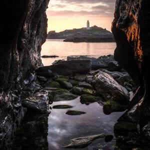 Godrevy Lighthouse at sunset, seen through rocksand rockpool in the foreground. Nr Hayle