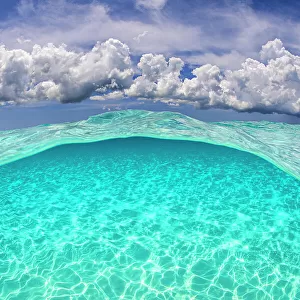 Light patterns on the seabed and fluffy cumulus clouds in the sky in a split level image. North Sound, Grand Cayman, Cayman Islands, British West Indies. Caribbean Sea