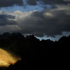 Mountain peaks and ridges in evening light, stormy skies above