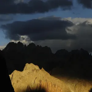 Mountain peaks and ridges in evening light, stormy skies above Mountain peaks and ridges in evening light, stormy skies above