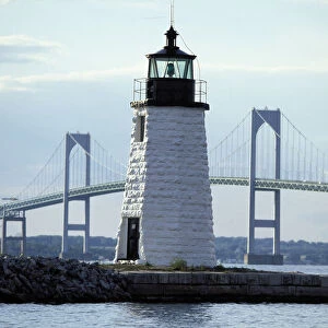 The Newport Harbor Light (Goat Island Light) standing framed by the giant Newport Bridge