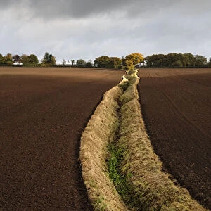 An open field ditch through farmland of recently ploughed fields, Wirral, Cheshire, UK. October, 2020