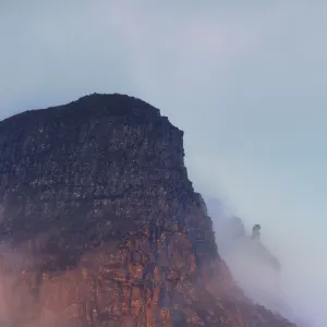 The rugged cliffs of Stac Pollidh in cloud and mist and lit by evening light