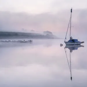 Sailing boat reflected in Wimbleball Lake in morning mist. Exmoor National Park, Somerset, England, UK. September 2020 Sailing boat reflected in Wimbleball Lake in morning mist. Exmoor National Park, Somerset, England, UK. September 2020
