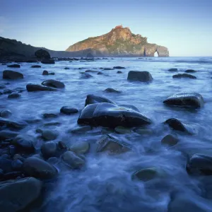 Sea over smooth rocks with rock arch in distance, Gaztelugatxe coast, Basque country