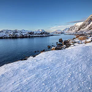 Snow over shore and mountains in winter, Henningvaer, Lofoten Islands, Norway. March, 2023