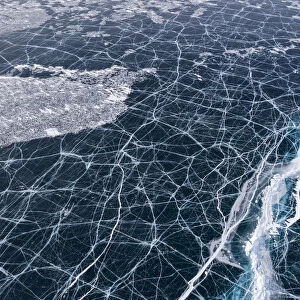 Transparent black ice with cracks on Lake Baikal, aerial shot