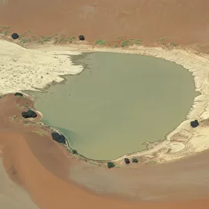 View of lake surrounded by sand dunes, with some vegetation growing around the edges