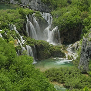 Waterfall and rapids falling into a mountain pool in woodland. Plitvice National Park