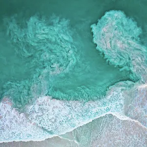 Waves crashing on beach and carrying sediments back out to sea, aerial view. The Bahamas