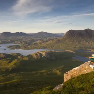 Woman meditating on Stac Pollaidh mountain with views of surrounding lochs and mountains, Assynt, Scotland, UK. July, 2017 Woman meditating on Stac Pollaidh mountain with views of surrounding lochs and mountains, Assynt, Scotland, UK. July, 2017