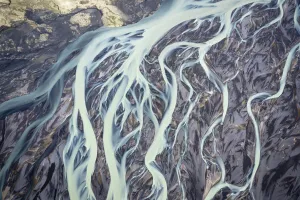 Climate Change Prints: Aerial view of a glacier river flowing from glacier which is melting at an unprecedented pace due to rising
