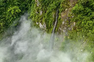 Fiji Prints: Aerial view of waterfall cascading down steep mountainside with low cloud