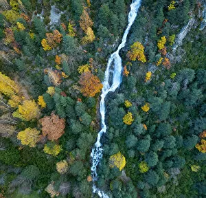 Aerial view of waterfall in the Urdiceto Ravine surrounded by mixed autumnal forest, Pyrenees Mountains, Aragon, Spain