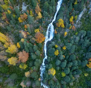 Aerial view of waterfall in the Urdiceto Ravine surrounded by mixed autumnal forest, Pyrenees Mountains, Aragon, Spain. November