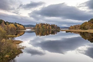 Autumn colours and stormy clouds reflected in the calm waters of Loch Insh, Cairngorms