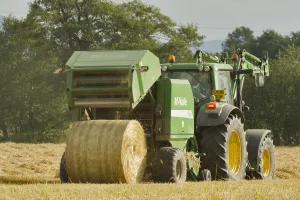 Harvesting Prints: Baling machine ejecting a bale of Barley straw on arable farmland, Scotland, UK