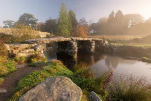 Clapper Bridge at Postbridge, early morning light and mist, Dartmoor National Park, Devon, UK. October 2018