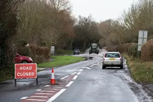 Information Prints: Closed road with an abandoned vehicle at roadside and a car and tractor driving through floodwater