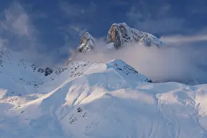 Summit Prints: Clouds surrounding snow-covered Midi d'Ossau peak in the evening