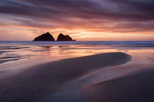 Holywell Bay at sunset, at low tide with Carters Rocks reflected in water