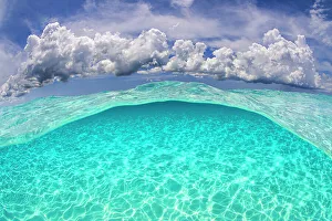 Blue Water Prints: Light patterns on the seabed and fluffy cumulus clouds in the sky in a split level image