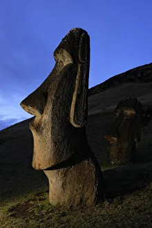 Moai stone statue at dusk on the slopes of the quarry at Rano Raraku volcano, Easter