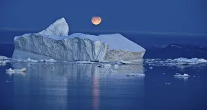 Full moon over an iceberg at dusk, Saqqaq, Disko Bay, Greenland, September 2009