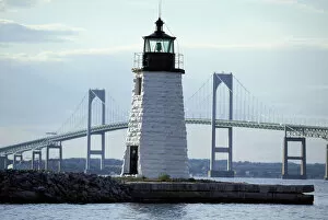 The Newport Harbor Light (Goat Island Light) standing framed by the giant Newport Bridge