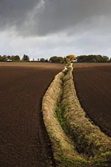An open field ditch through farmland of recently ploughed fields, Wirral, Cheshire, UK. October, 2020