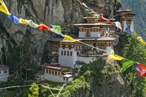 Paro Taktsang / Tigers Nest Buddhist monastery perched on cliffs with prayer flags