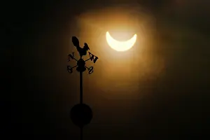 Natural Phenomenon Prints: Partial solar eclipse above silhouette of weather vane, Wroclaw, Poland. 3rd March, 2015