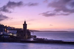 Porthleven clocktower and harbour with coastline beyond, at sunrise
