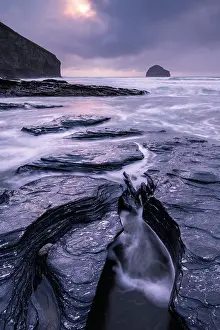RF - Trebarwith Strand at twilight with the rising tide surrounding the rocky ledges along the shore, Trebarwith, Cornwall, England, UK. March, 2023