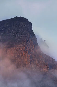The rugged cliffs of Stac Pollidh in cloud and mist and lit by evening light