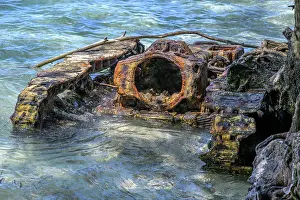 Submerging Prints: Rusty remains of old WW2 vehicle partially submerged on beach