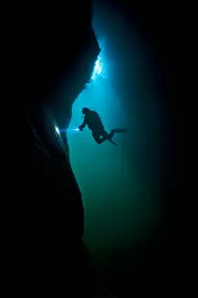 Scuba diver exploring a sea cave beneath Giants Legs, Bressay, Shetland Islands, Scotland