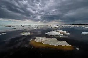 Arctic Ocean Prints: Sea ice breaking up and melting under a cloudy sky in spring