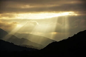 Images Dated 9th September 2015: Shafts of light at dusk over Wrynose pass and the Coniston hills from Ambleside, Lake District