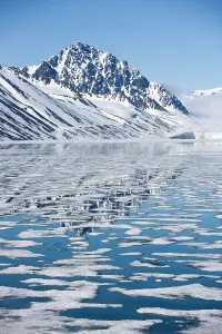 Arctic Ocean Prints: Snow-covered mountains reflecting on drifting and melting sea ice